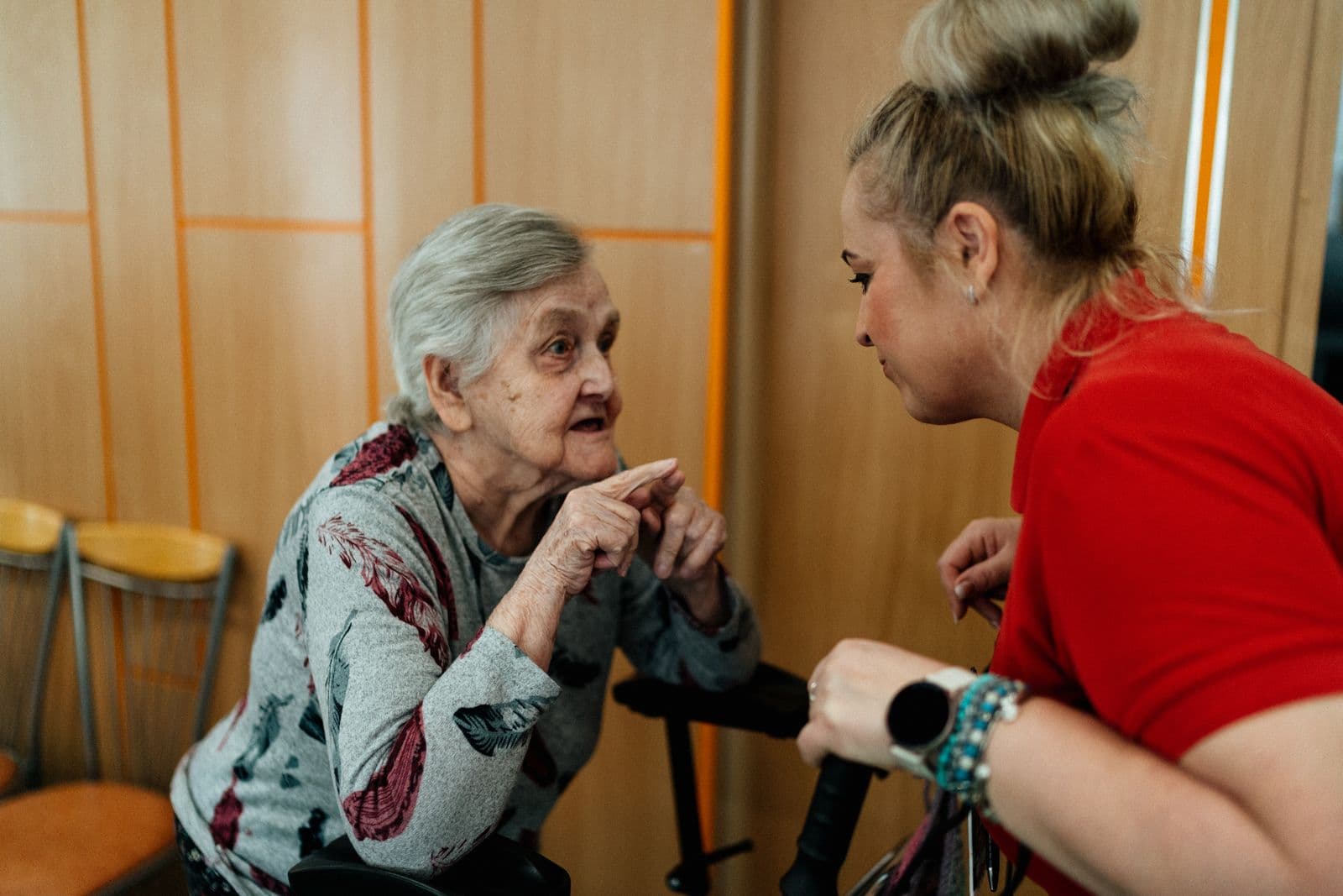 A caregiver sits with an older woman at home.