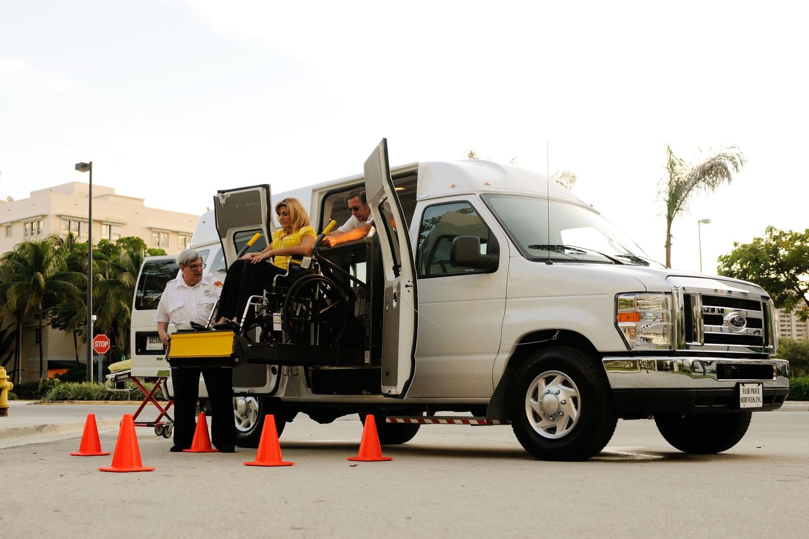 A wheelchair lift moves a person into an accessible van in daylight.